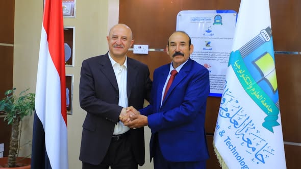 صورة رسمية تجمع رئيس جامعة العلوم و أ.د علي سعيد الطارق يقفان بجانب علم الجمهورية اليمنية وعلم جامعة العلوم والتكنولوجيا.
